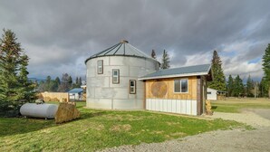 Un edificio rústico de dos pisos con un silo cilíndrico adosado a la estructura principal.