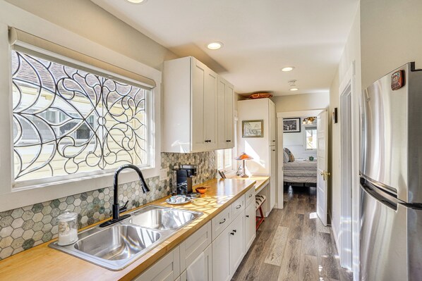 A modern kitchen with a large window, stainless steel appliances, and a wooden countertop.