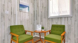Two green upholstered chairs with wooden frames and a small table with a welcome sign and a potted plant between them. - Pet-friendly Picayune Tiny Home: 4 Mi to Dtwn! (Picayune)