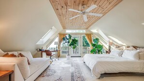 A spacious attic bedroom with a large bed, a sofa, a desk, and a ceiling fan. - Pacific View Home: Hot Tub & Ocean/valley Views! (Langlois)