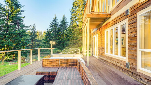 A wooden deck with outdoor seating, surrounded by trees. - Pacific View Home: Hot Tub & Ocean/valley Views! (Langlois)