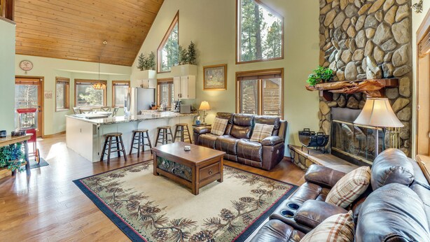 A spacious living area with a stone fireplace, leather sofas, a wooden ceiling, and large windows. - Golf, Hike, Explore! Family-friendly Pinetop Haven (Pinetop)