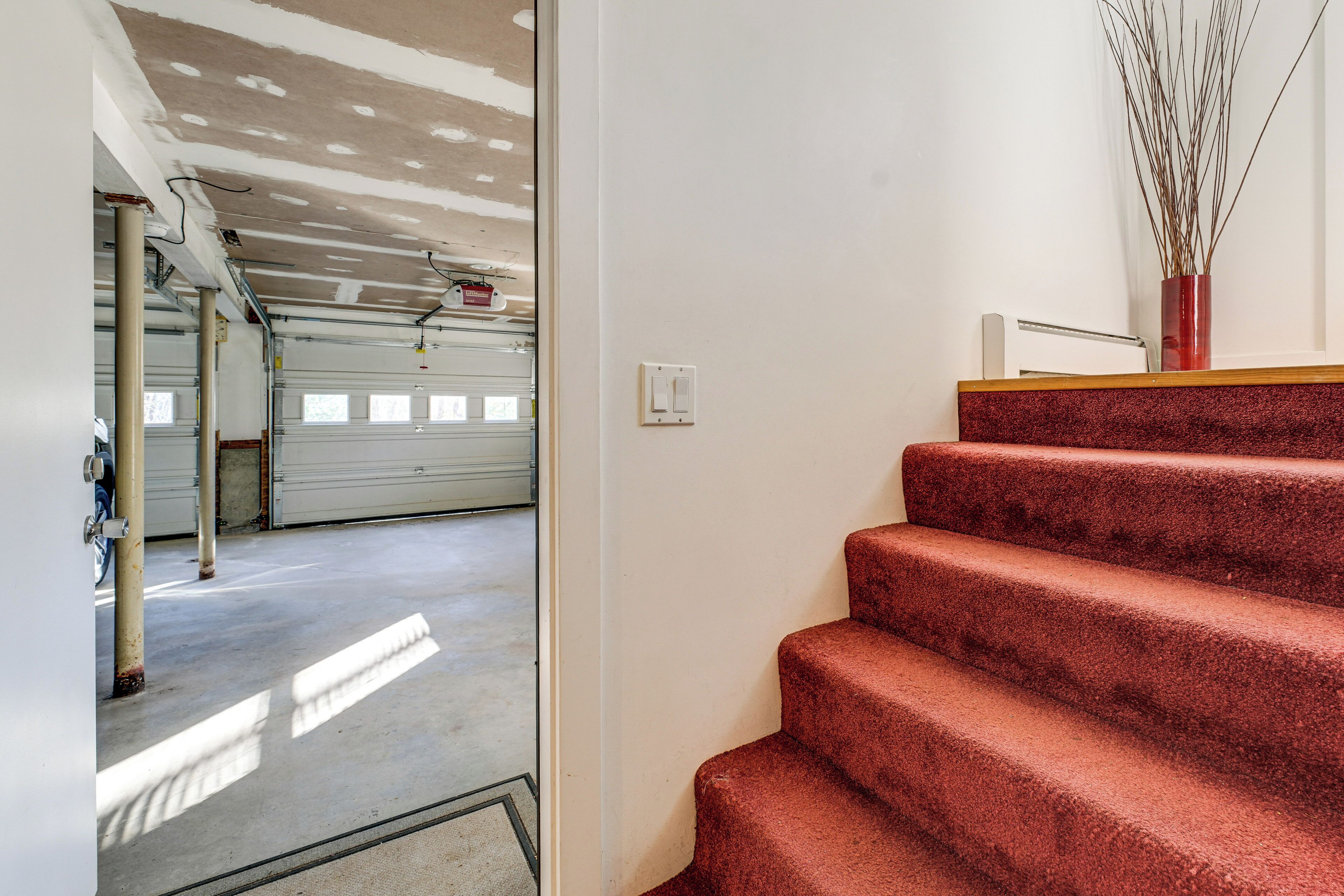 Una scala conduce a un garage con pavimento in cemento e parete bianca.