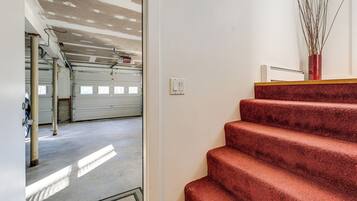 Una scala conduce a un garage con pavimento in cemento e parete bianca.