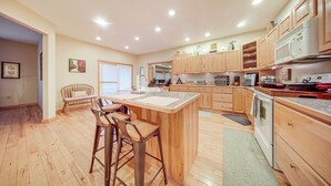A spacious kitchen with wooden cabinets, a central island with stools, and modern appliances. - Family & Pet Friendly! 7-acre Escape in Jefferson (Jefferson)