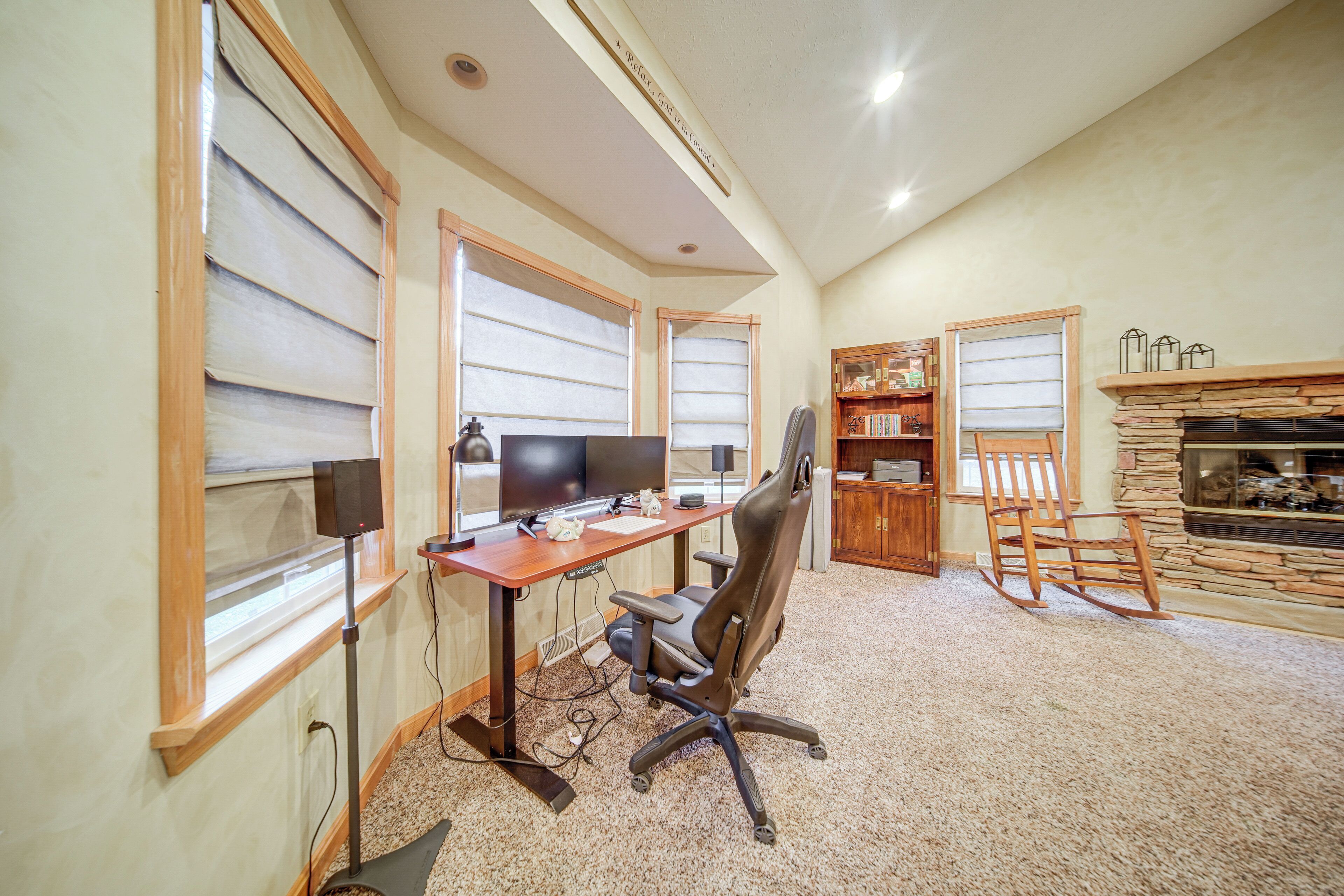 A home office with a desk, two monitors, a chair, and a fireplace.