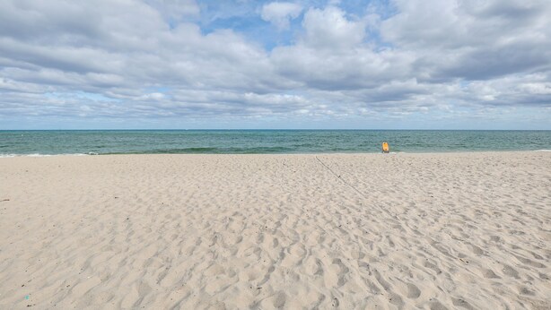 A wide sandy beach with gentle waves and a clear sky. - 1 Mi to Pompano Beach Pier: Pet-friendly Studio! (Pompano Beach)
