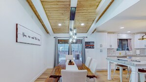 Une cuisine moderne avec des meubles blancs, un plan de travail en bois et un luminaire suspendu.