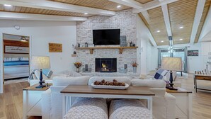 Un salon moderne avec une cheminée, des canapés blancs et un plafond en bois.