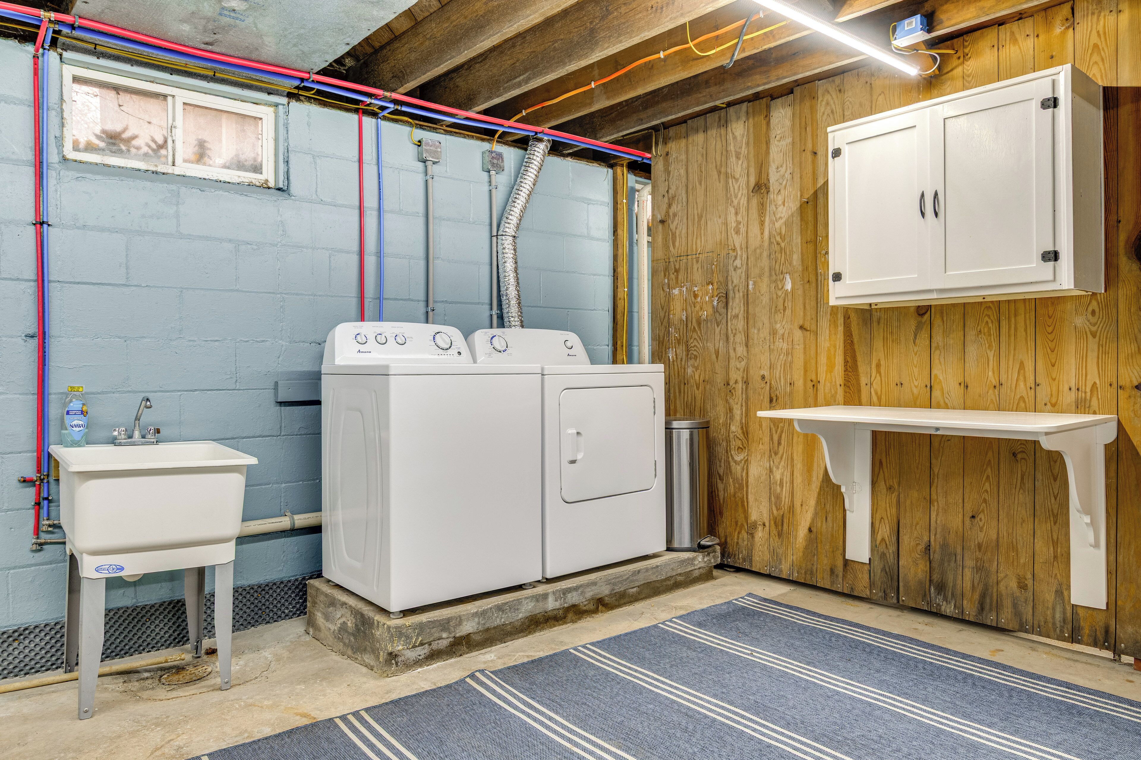 A laundry room with a washing machine, a sink, and a cabinet.