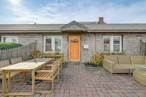 Et hus med træfacade, fliseterrasse og udendørs møbler.