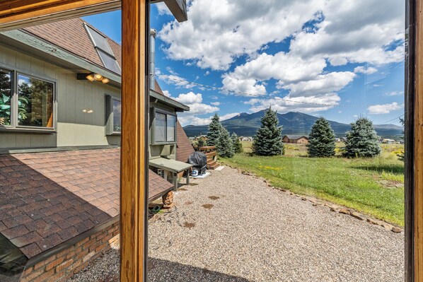 A house with a gravel driveway, wooden deck, and a mountain view.