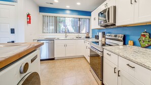 A modern kitchen with white cabinets, a stainless steel microwave, and a built-in oven.
