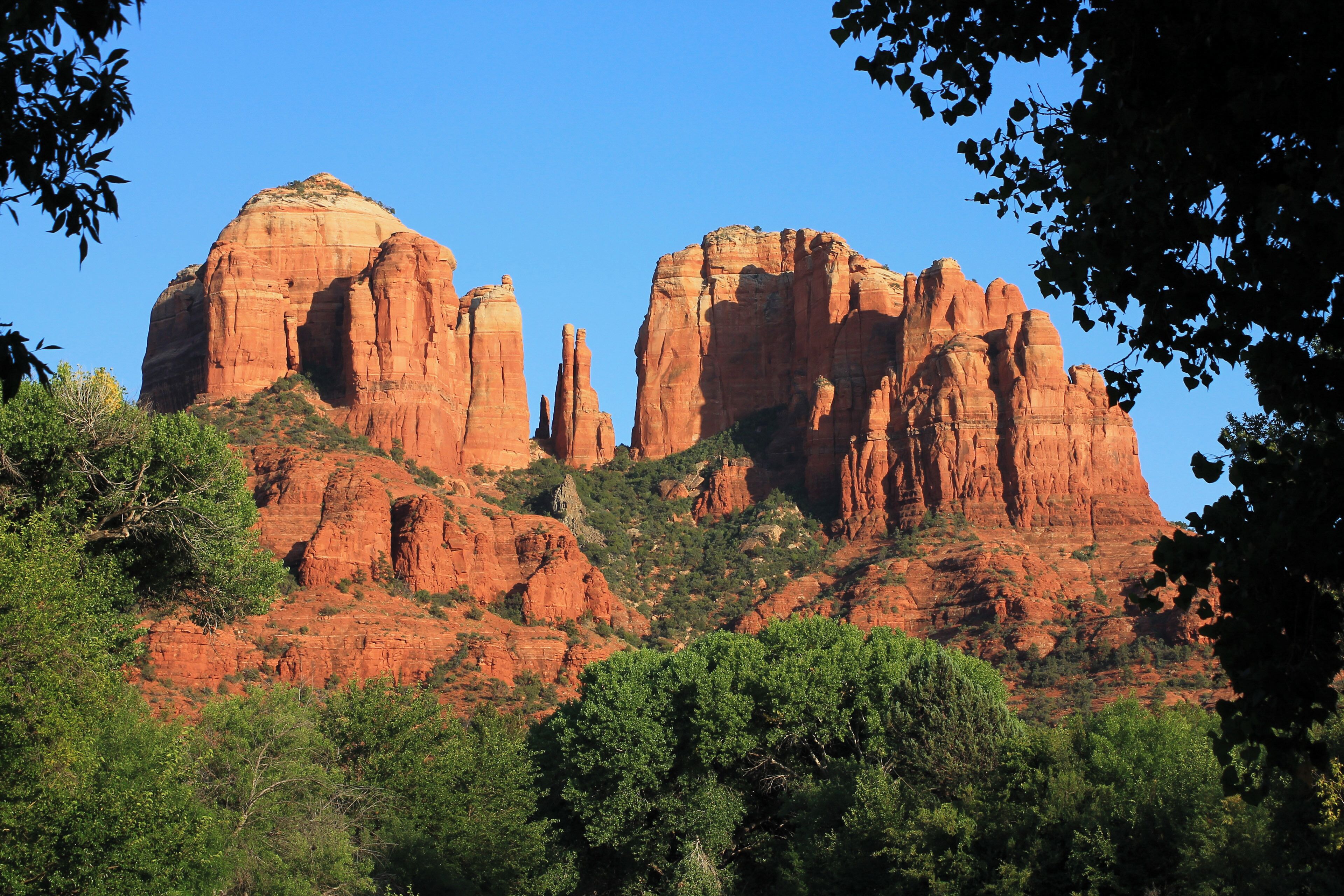 A natural landscape with prominent red rock formations and green vegetation.