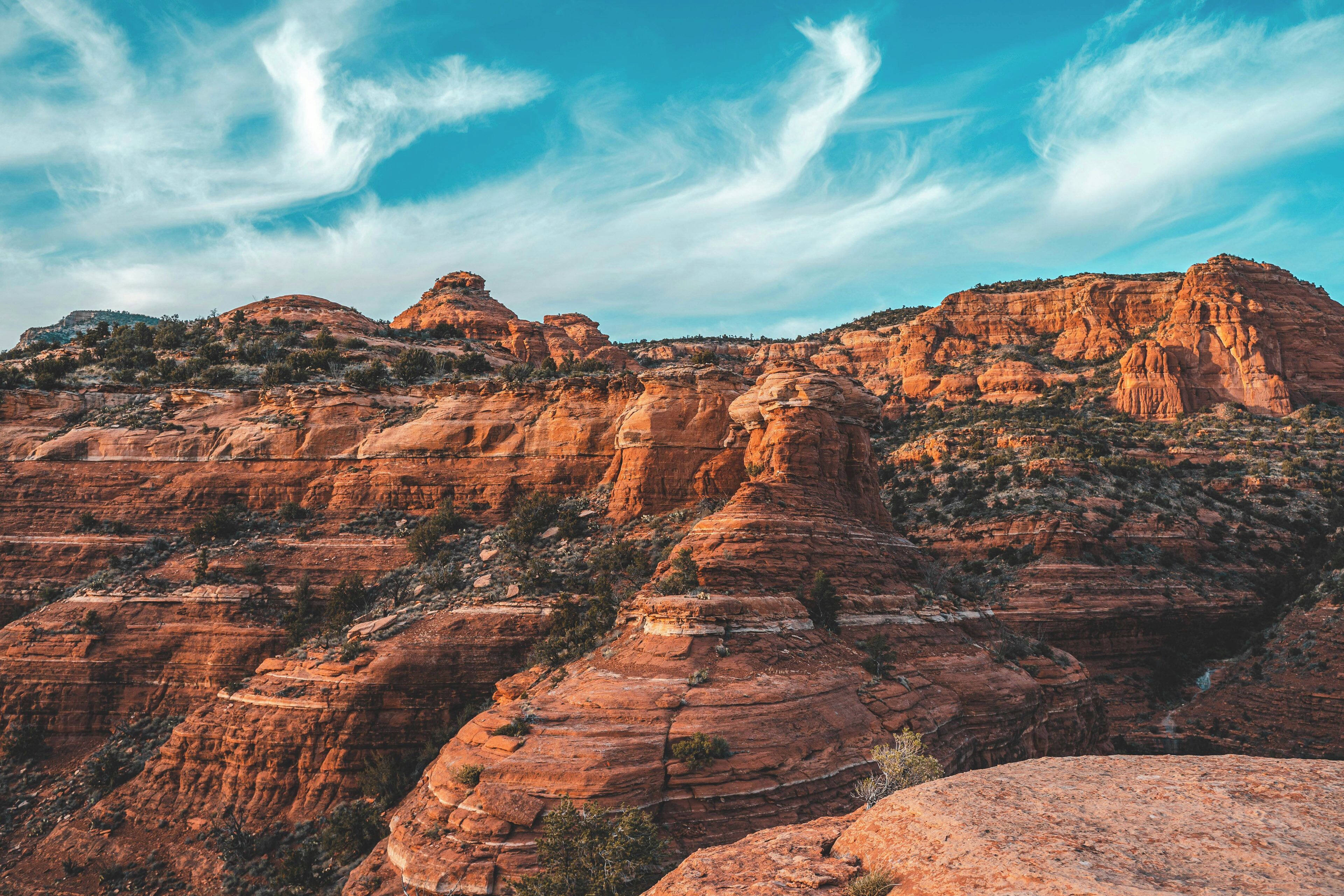 A rugged canyon landscape with layered rock formations and sparse vegetation.