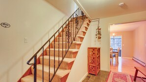 A staircase with a wooden handrail and carpeted steps leading to a dining area.