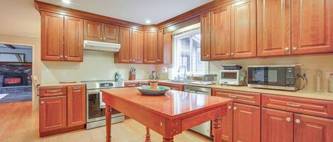 A kitchen with wooden cabinets, a central island, stainless steel appliances, and a window providing natural light.