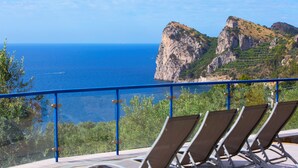 Ein Balkon mit Liegestühlen und Blick auf die Küste, Klippen und das Meer.