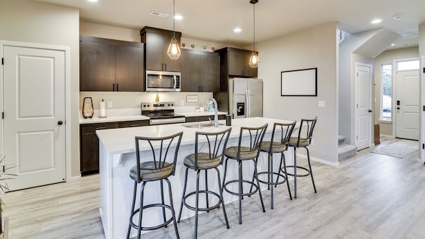 A modern kitchen with a central island, bar stools, and built-in appliances. - Family Friendly! Newly Built North Vancouver Home! (Vancouver)