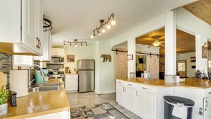 Une cuisine moderne avec des armoires blanches, des appareils en acier inoxydable et un plan de travail en bois.