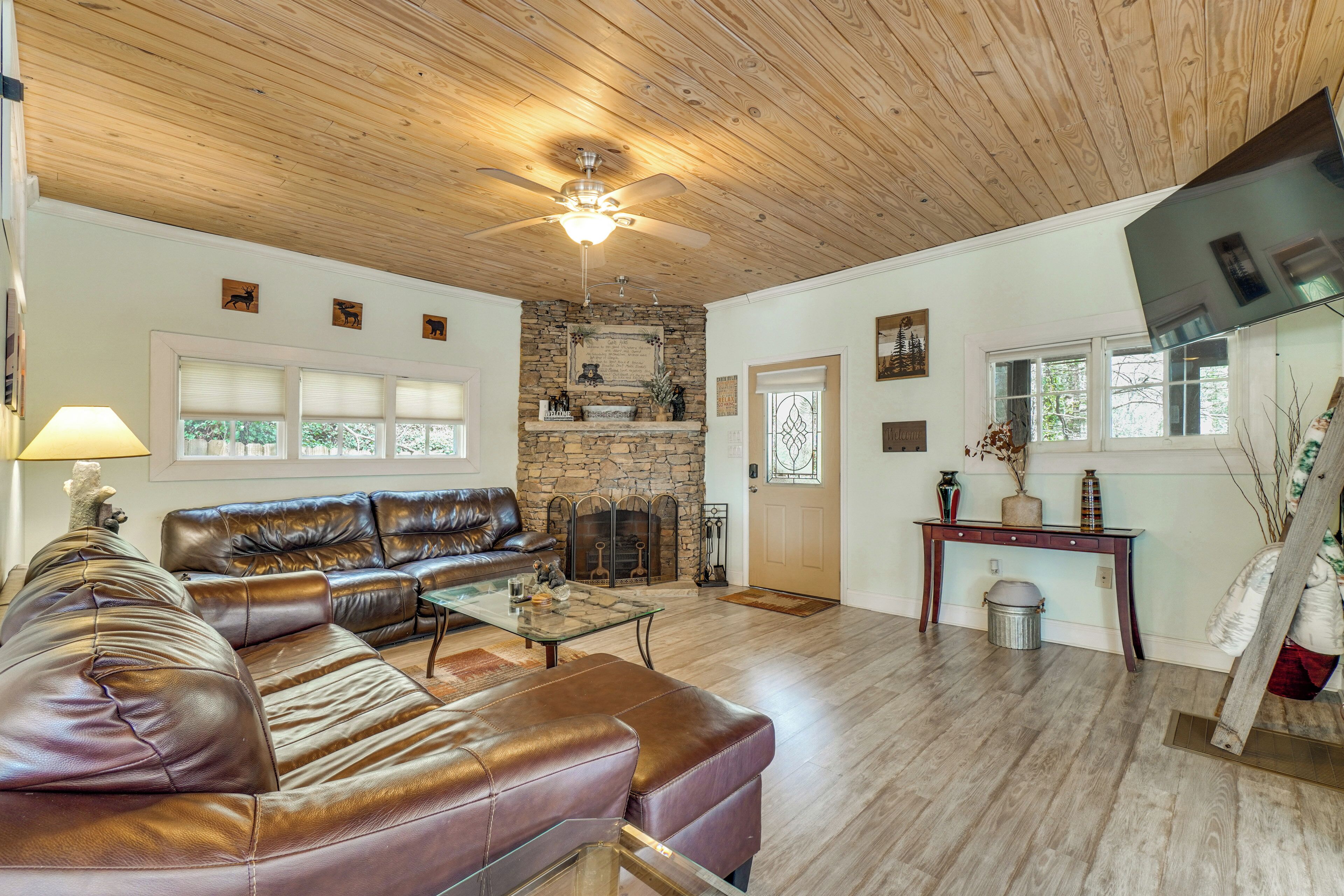 A living room with a leather sofa, fireplace, and wooden floors.