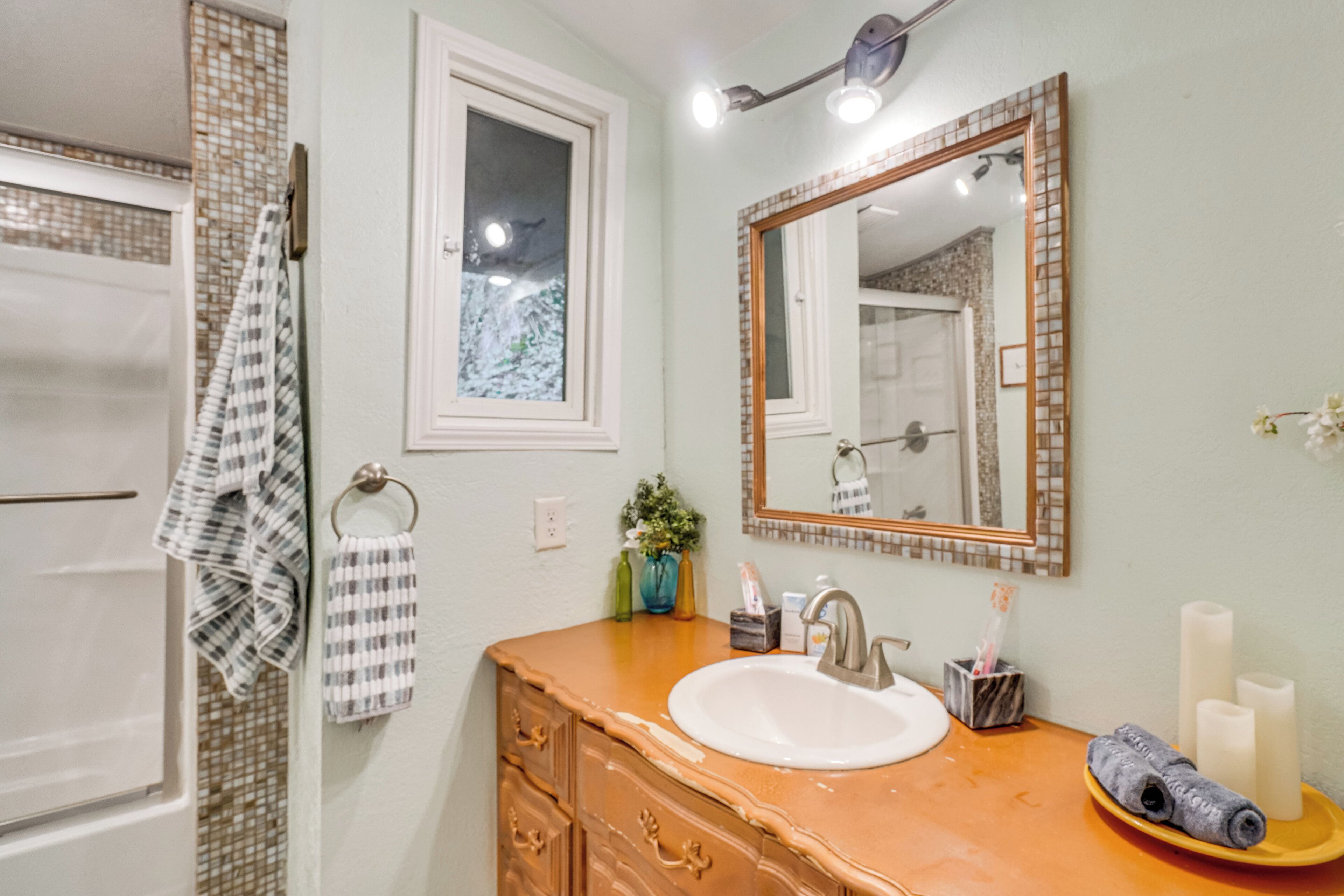 Un baño con un lavabo blanco, un espejo y un perchero para toallas.
