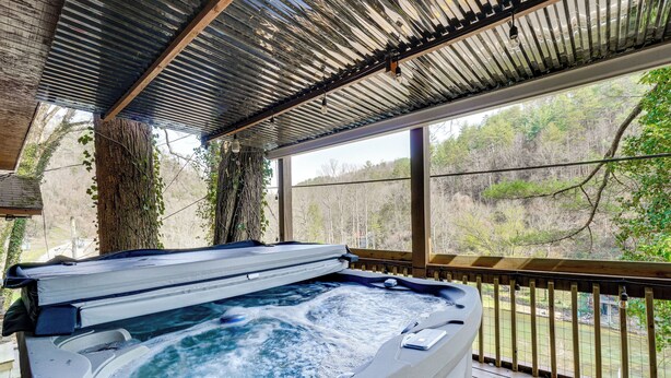Un bain à remous avec une terrasse en bois et vue sur une forêt.