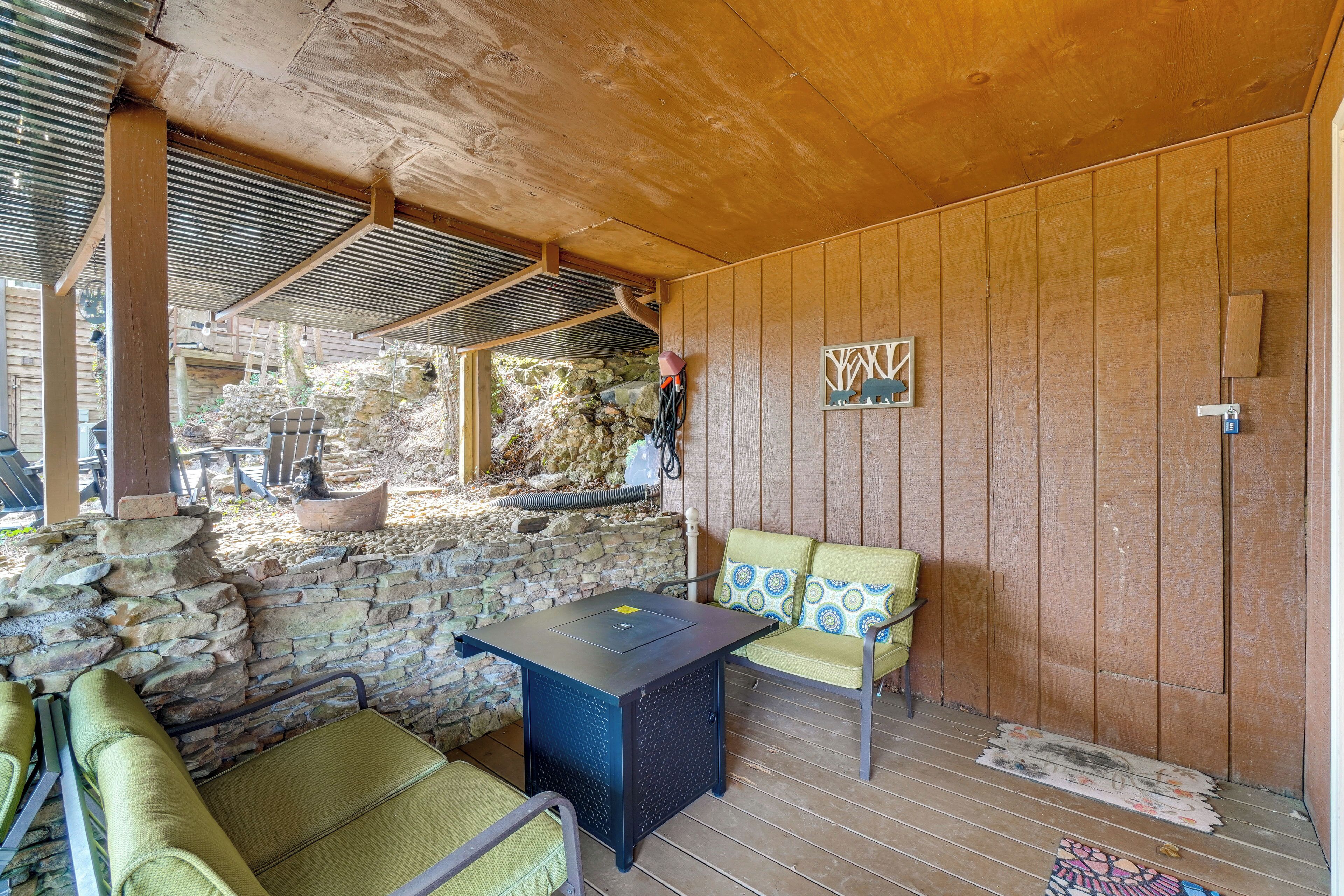 A covered outdoor seating area with stone walls, a table, and chairs.