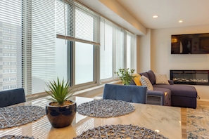 A modern living room with a large window, a flat-screen TV, and a fireplace. - Cozy 12th-floor Studio w/ Lake Erie Views! (Lakewood)