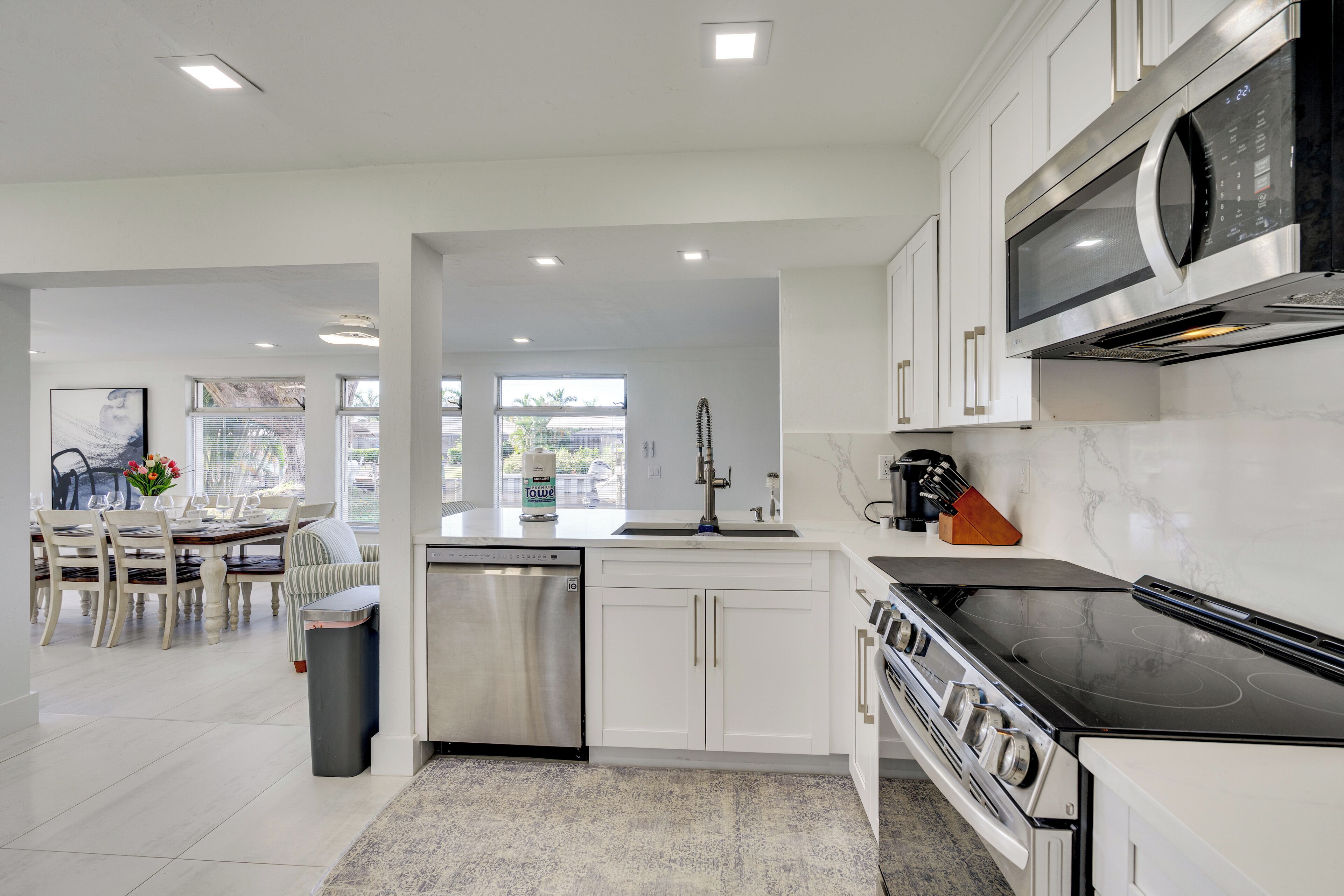 A modern kitchen with white cabinetry, stainless steel appliances, and a dining area with a table and chairs.