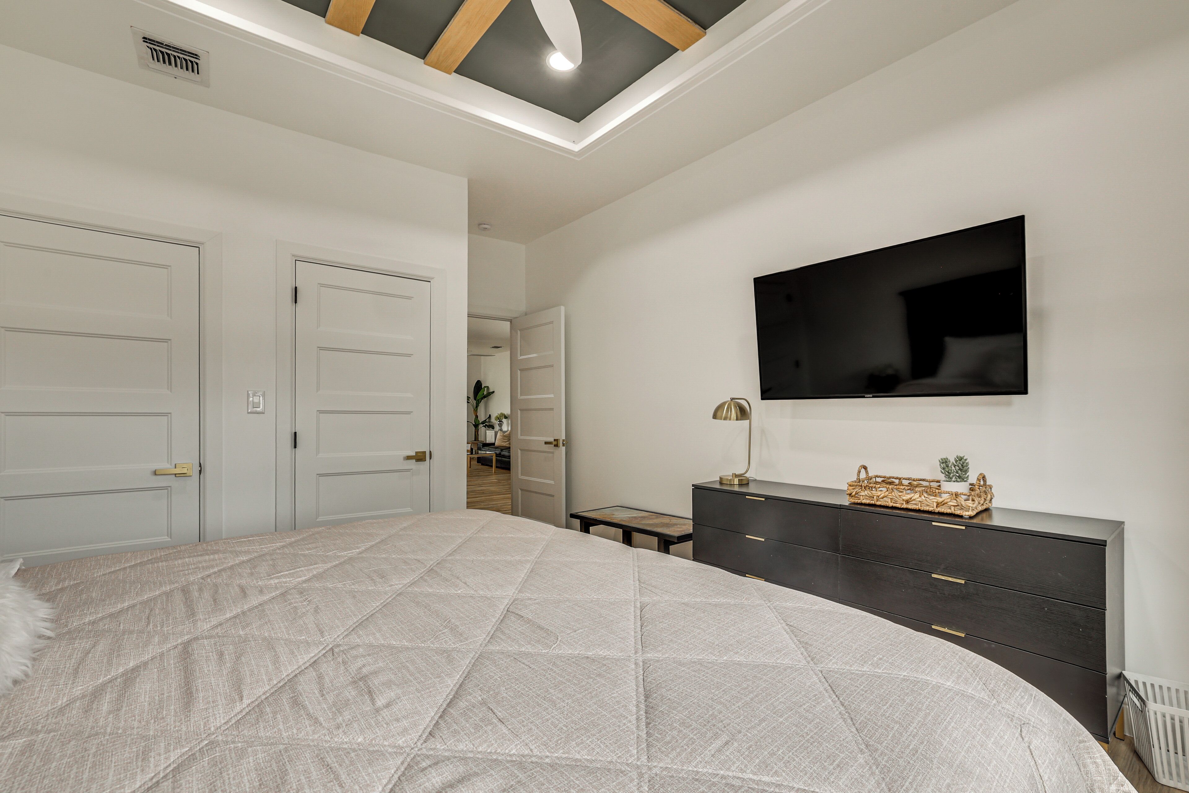Un dormitorio con cama, cómoda, televisor y luz en el techo.