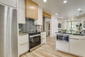 A modern kitchen with stainless steel appliances, wooden cabinets, and a marble backsplash. - River Walk, Frost Center, Alamodome, Fort Sam Hous (San Antonio)