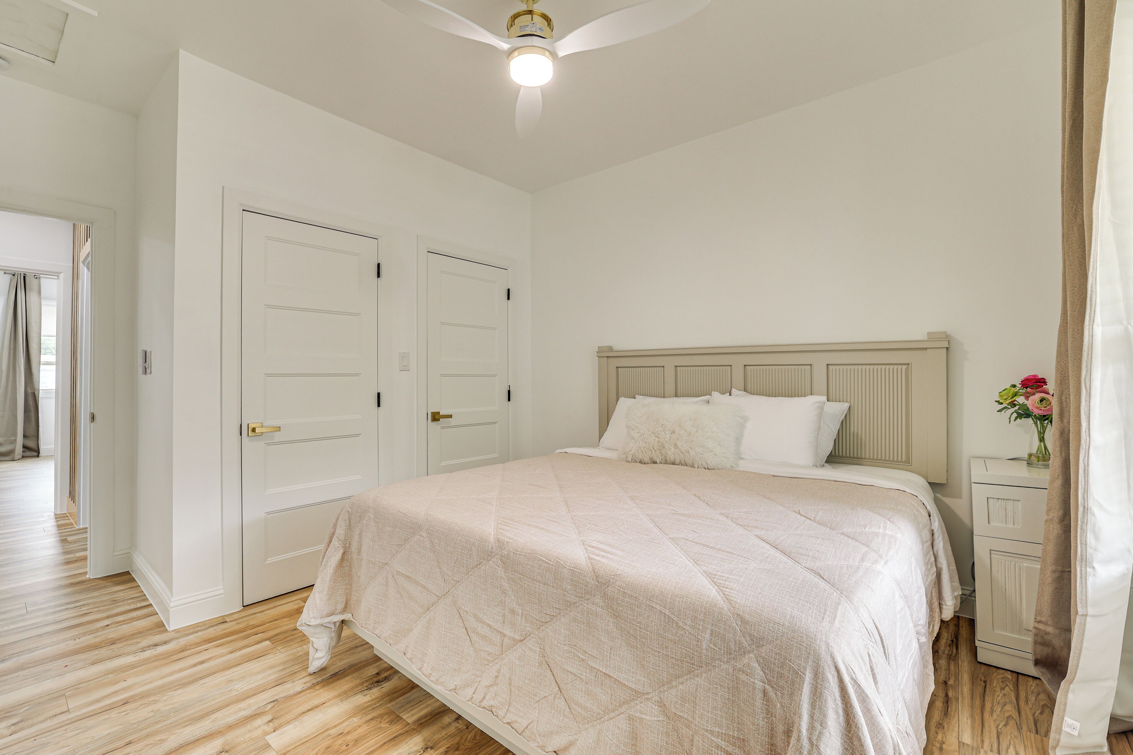 Ein Schlafzimmer mit Bett, Nachttisch, Kommode und Deckenventilator.