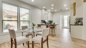 Une cuisine moderne dotée d’un îlot central, d’un coin repas avec une table en verre et offrant une vue dégagée grâce à de grandes fenêtres.
