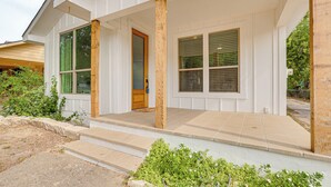 Une maison à deux étages avec un porche couvert, de grandes fenêtres et une porte d’entrée.