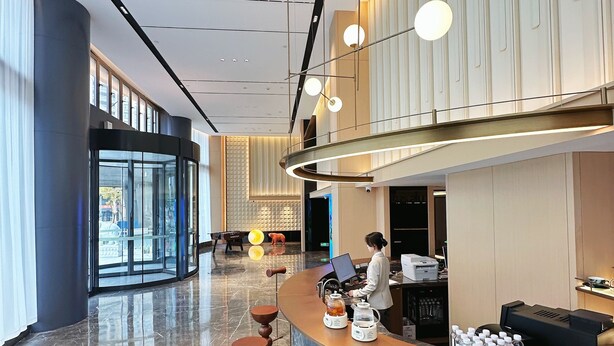 Un hall d’hôtel comprenant un comptoir d’accueil, un espace salon et une grande fenêtre donnant sur l’extérieur.