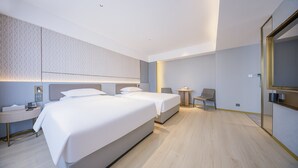 Une chambre d’hôtel moderne avec deux lits, une table de chevet, une petite table ronde et une chaise.