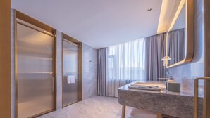 Une salle de bain moderne avec un lavabo en marbre, un grand miroir et une douche à l’italienne dotée de portes en verre dépoli.