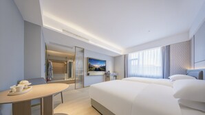 Une chambre d’hôtel moderne équipée d’un grand lit, d’un bureau, d’une chaise, d’une télévision et d’une salle de bain avec douche et miroir.