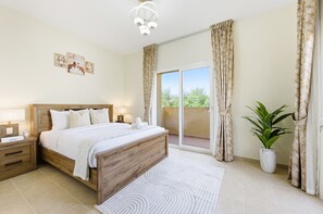 A bedroom with a wooden bed, a nightstand, a bedside table, a large window with curtains, and a potted plant. - Serene 2BR Villa, Minutes Drive to Miracle Garden and Dubai Butterfly Garden (Dubai)