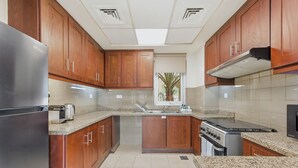 Eine Küche mit Holzausstattung, einem Edelstahlkühlschrank, einem eingebauten Backofen und einer Arbeitsplatte aus Granit.