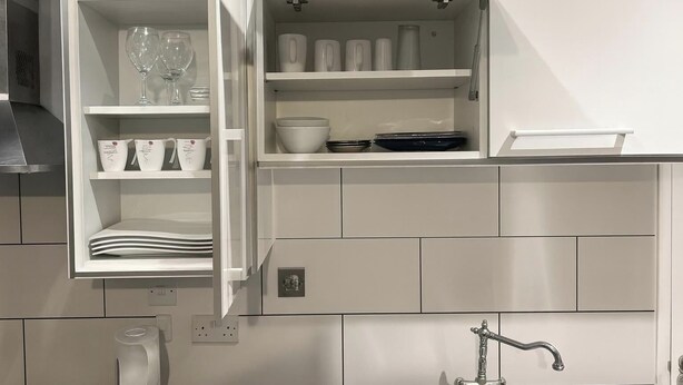 A kitchen with white cabinets, a built-in oven, and a sink with a faucet. - Charming High Wycombe Apartment (High Wycombe)