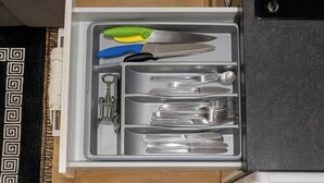 A drawer with utensils including a knife, forks, and a corkscrew. - Charming High Wycombe Apartment (High Wycombe)