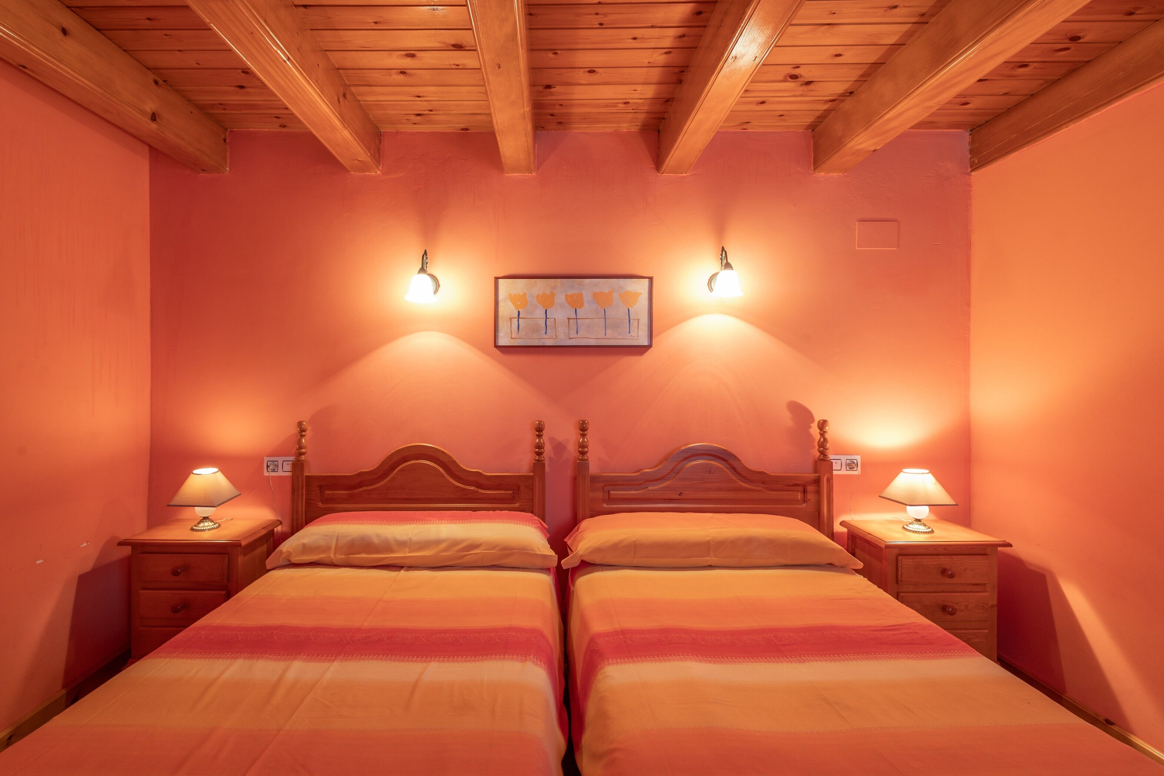 Ein Zimmer mit zwei Holzbett, Nachttischen mit Lampen und einer Wandleuchte.