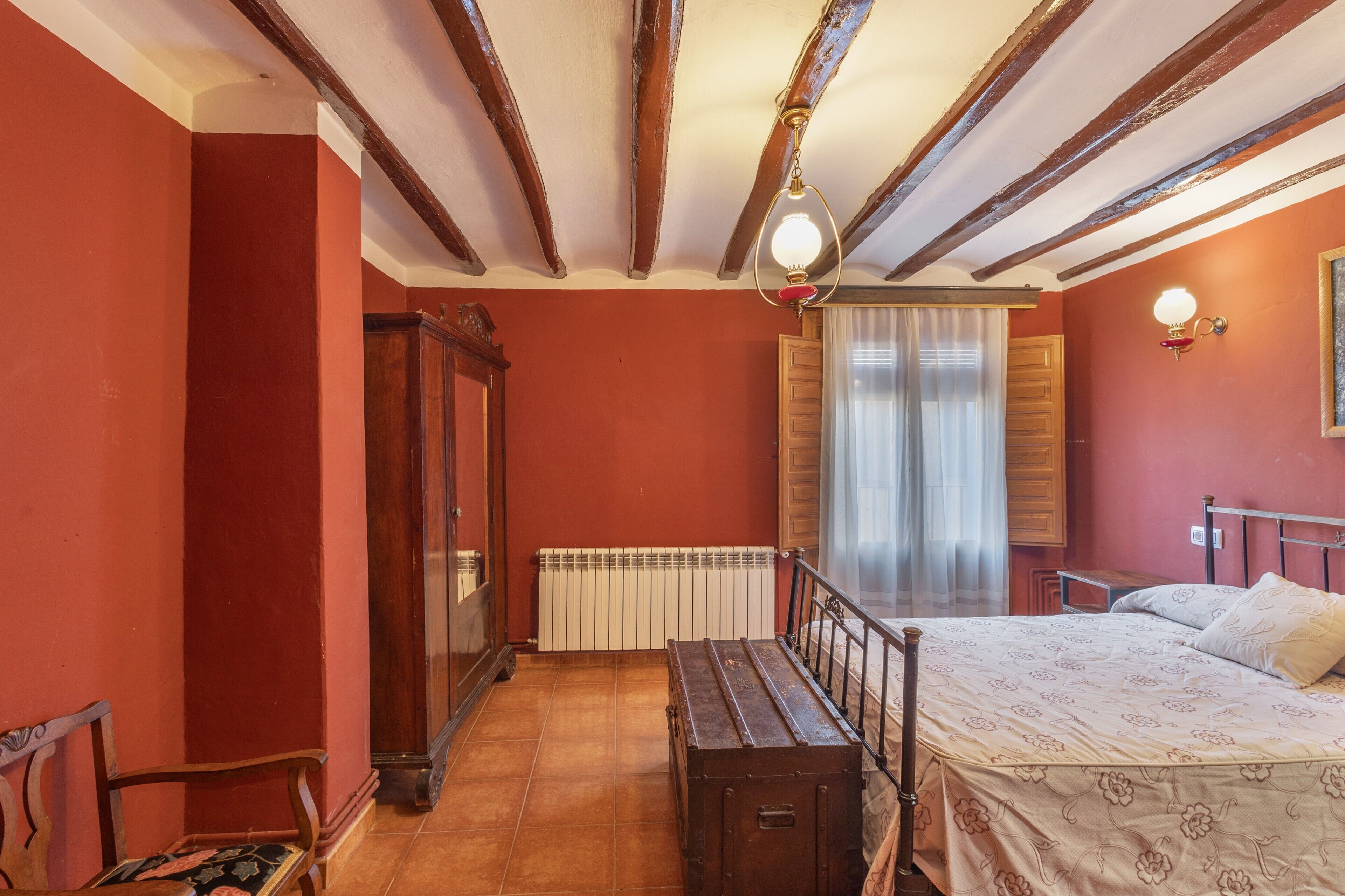 Un dormitorio con cama de madera, un radiador, un armario de madera y un banco.