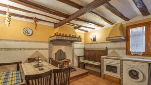 Una cocina con una mesa de comedor, sillas, horno empotrado, lavadora y un reloj decorativo de pared.