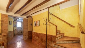 Una escalera con barandilla, perchero y tablón de anuncios en una pared amarilla.