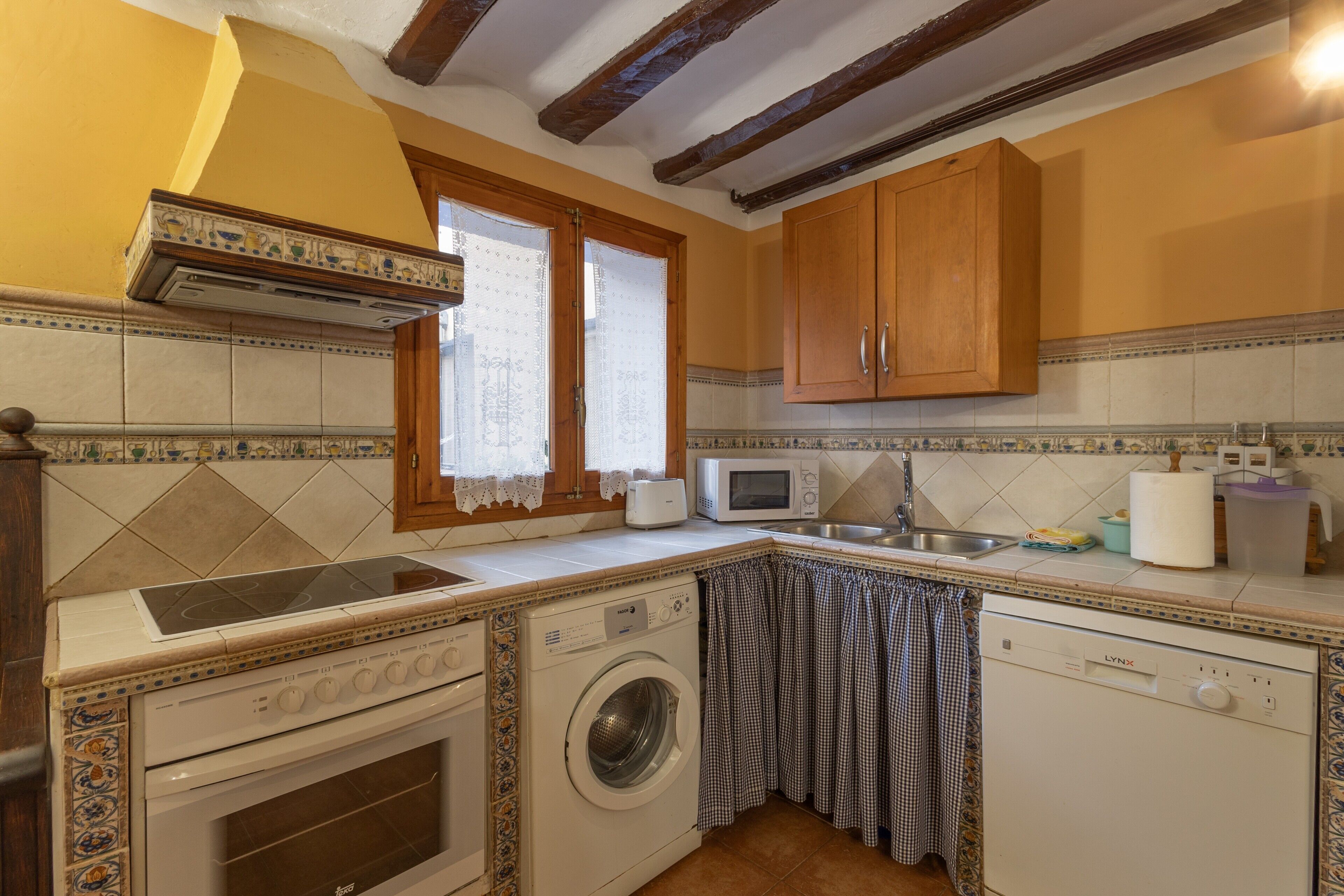 Una cucina compatta con lavatrice, forno a microonde e forno integrato.