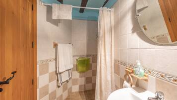 Een badkamer met een douche, wastafel, spiegel en handdoekhouder.
