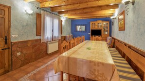Un comedor con una mesa larga, sillas de madera y una pared de piedra.